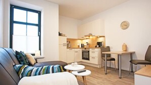 A modern living room with a sofa, coffee table, and a dining area with chairs. - Residenz zum Südstrand - Kutte (Borkum)