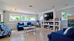 Un salón amplio con un sofá azul, una mesa de centro y una estantería llena de libros.