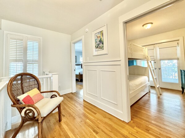 A room with wooden flooring, a wooden chair with a cushion, a bunk bed, and a ladder. - Seaside, FL Beach Home - Close to Pool & Beach; + 2 Adult Bikes! (Santa Rosa Beach)