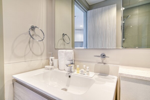 A modern bathroom with a white sink, a mirror, and a towel rack.