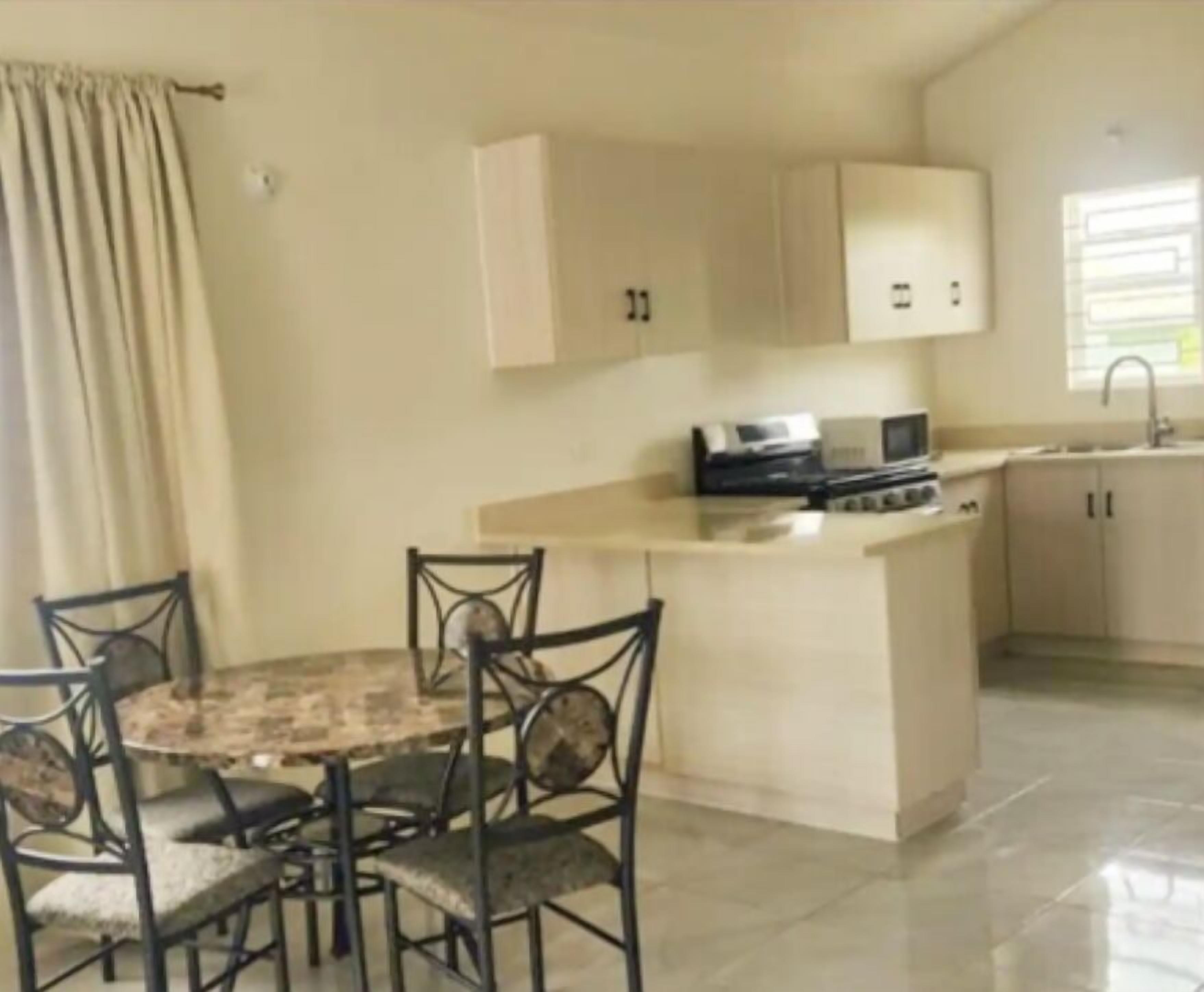 A compact kitchen with a dining area, including a round table and four chairs.