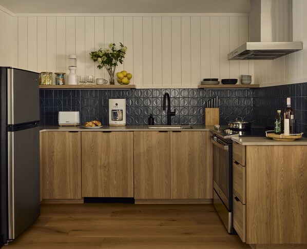 Eine moderne Küche mit Holzausstattung, einem Backofen, einer Kaffeemaschine und einem Spülbecken.