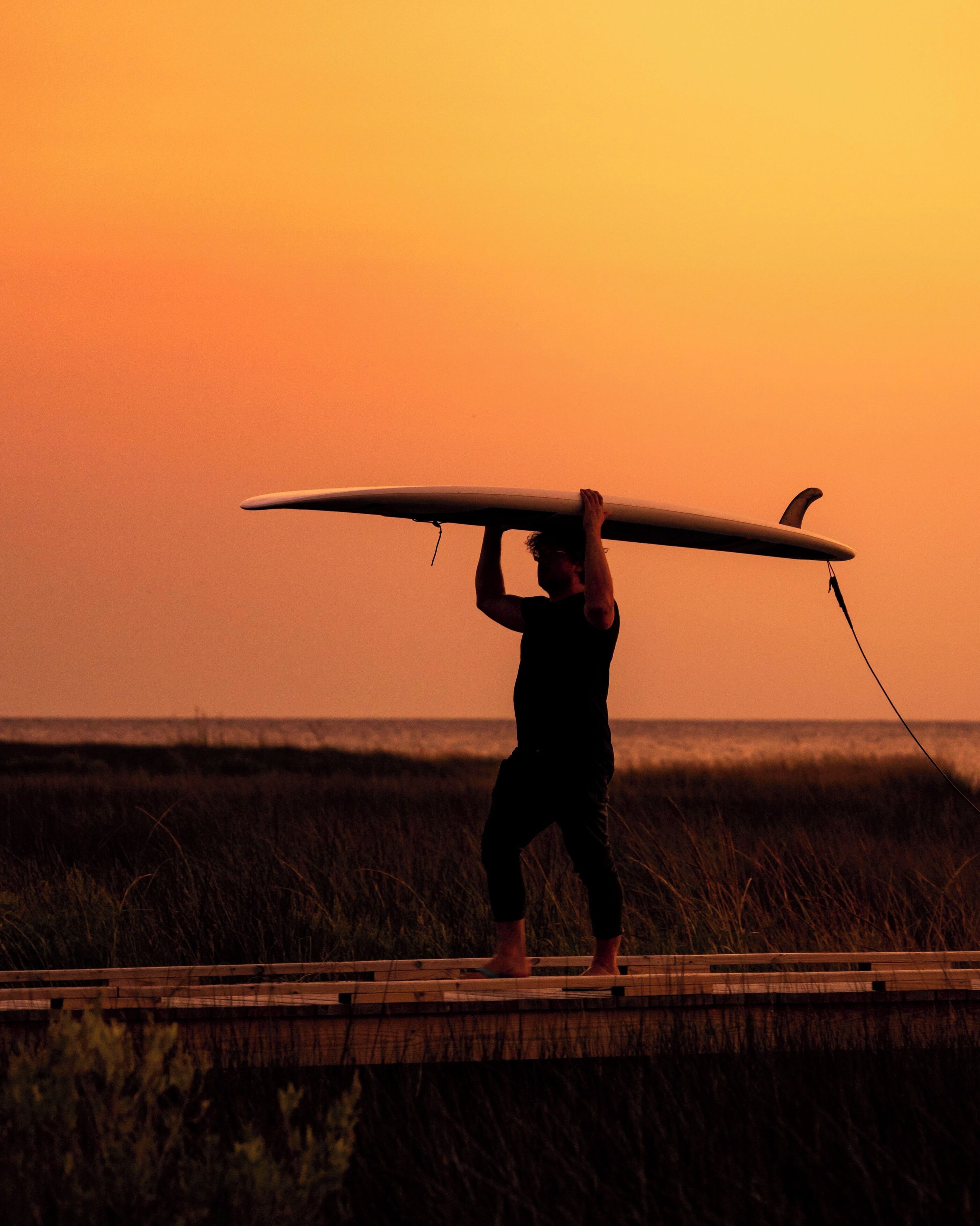 Une personne qui porte une planche de surf sur la tête.