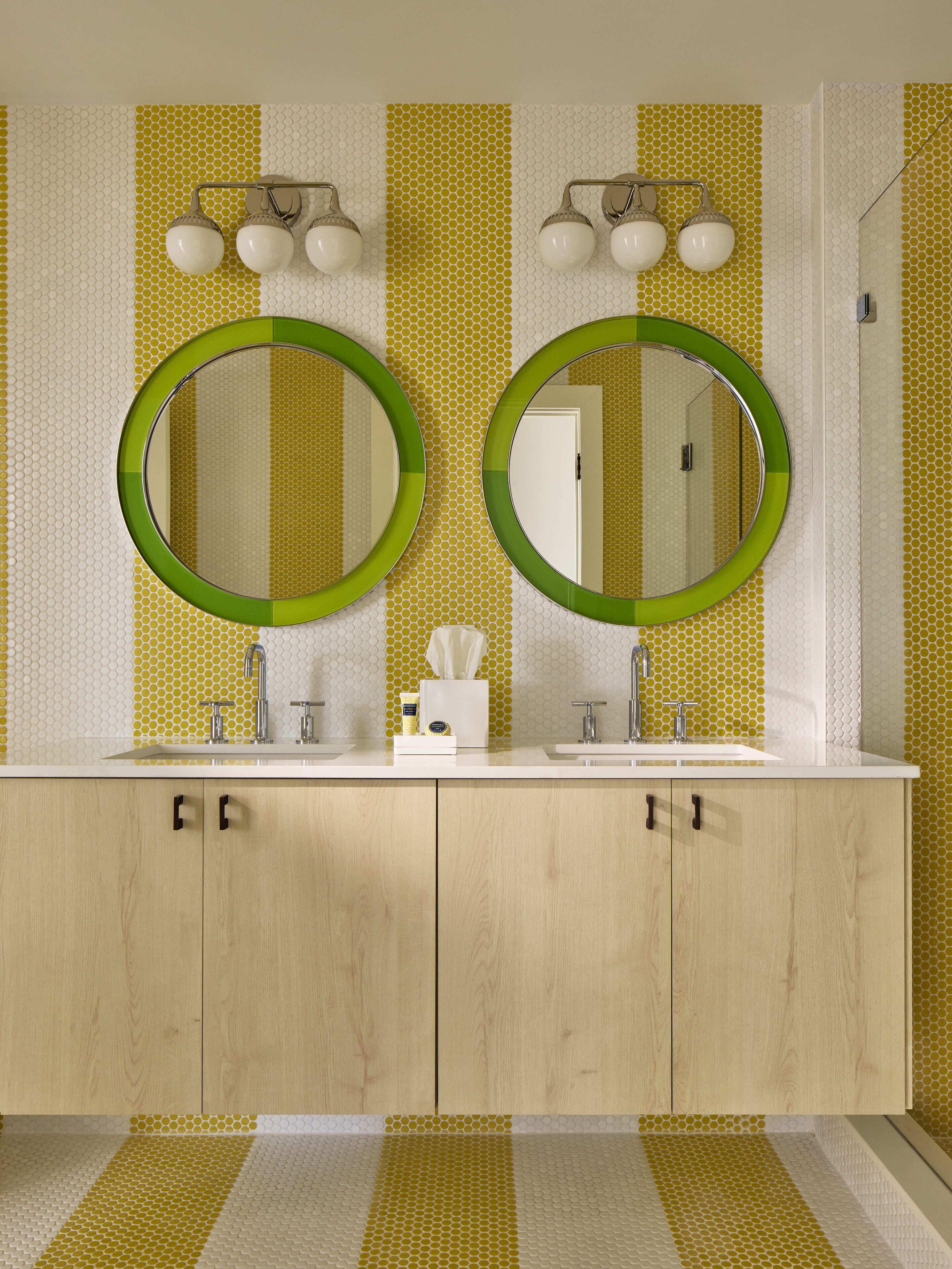 A bathroom with two sinks, a mirror, and a towel dispenser.