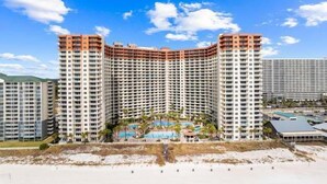 Un hôtel de grande hauteur à la façade incurvée, doté de nombreux balcons et d’une cour intérieure avec des piscines.