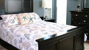 Um quarto com cama, ventilador de teto, decoração com leme de navio e cômoda.