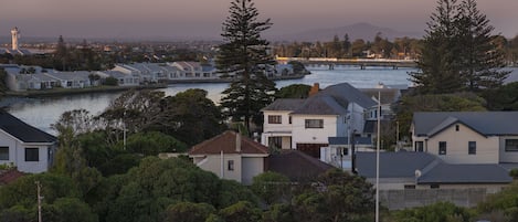 A residential area with houses near a body of water, a lighthouse in the distance, and a speed limit sign of 60.
