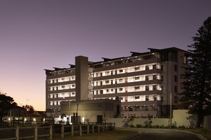 A multi-story hotel with a modern architectural design, featuring balconies and a central courtyard.