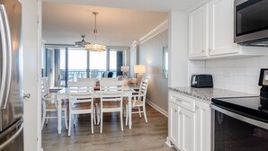 A modern kitchen with white cabinetry, a built-in microwave, and a large window overlooking a balcony. - Fantastic upgraded Station One condo (Wrightsville Beach)