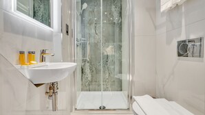 A modern bathroom with a glass-enclosed shower, a white sink, and a towel rack. - Cleveland Residences Farringdon (London)