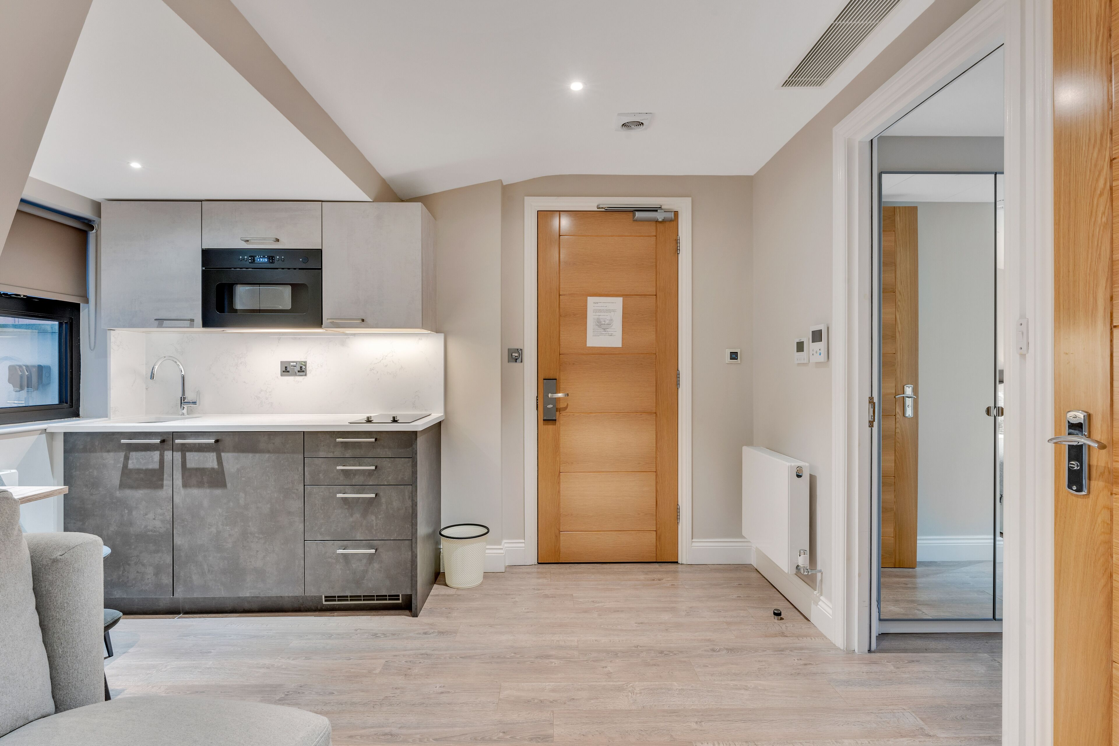 A modern kitchen with grey cabinets, a built-in oven, and a white countertop.