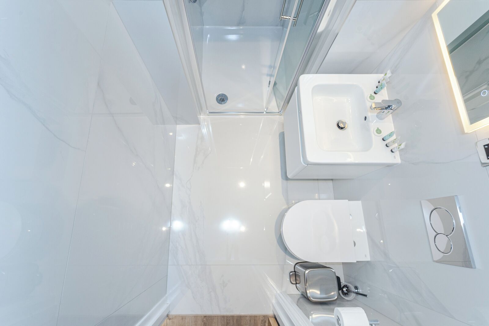 A modern bathroom with a glass shower enclosure, a white sink, and a toilet.