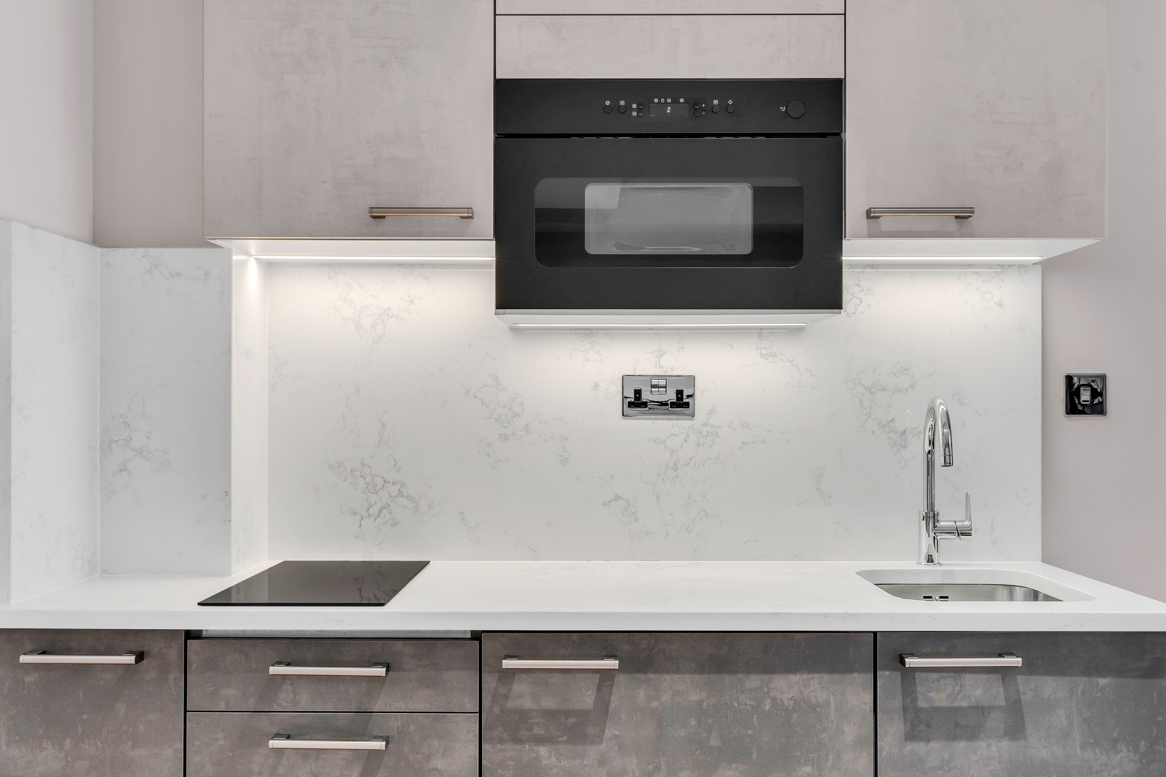 Una cocina moderna con horno empotrado, un lavamanos y una encimera.