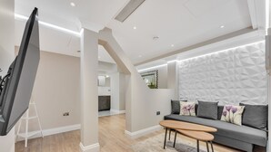 A modern living room with a sofa, coffee table, and a flat-screen TV. - Cleveland Residences Farringdon (London)