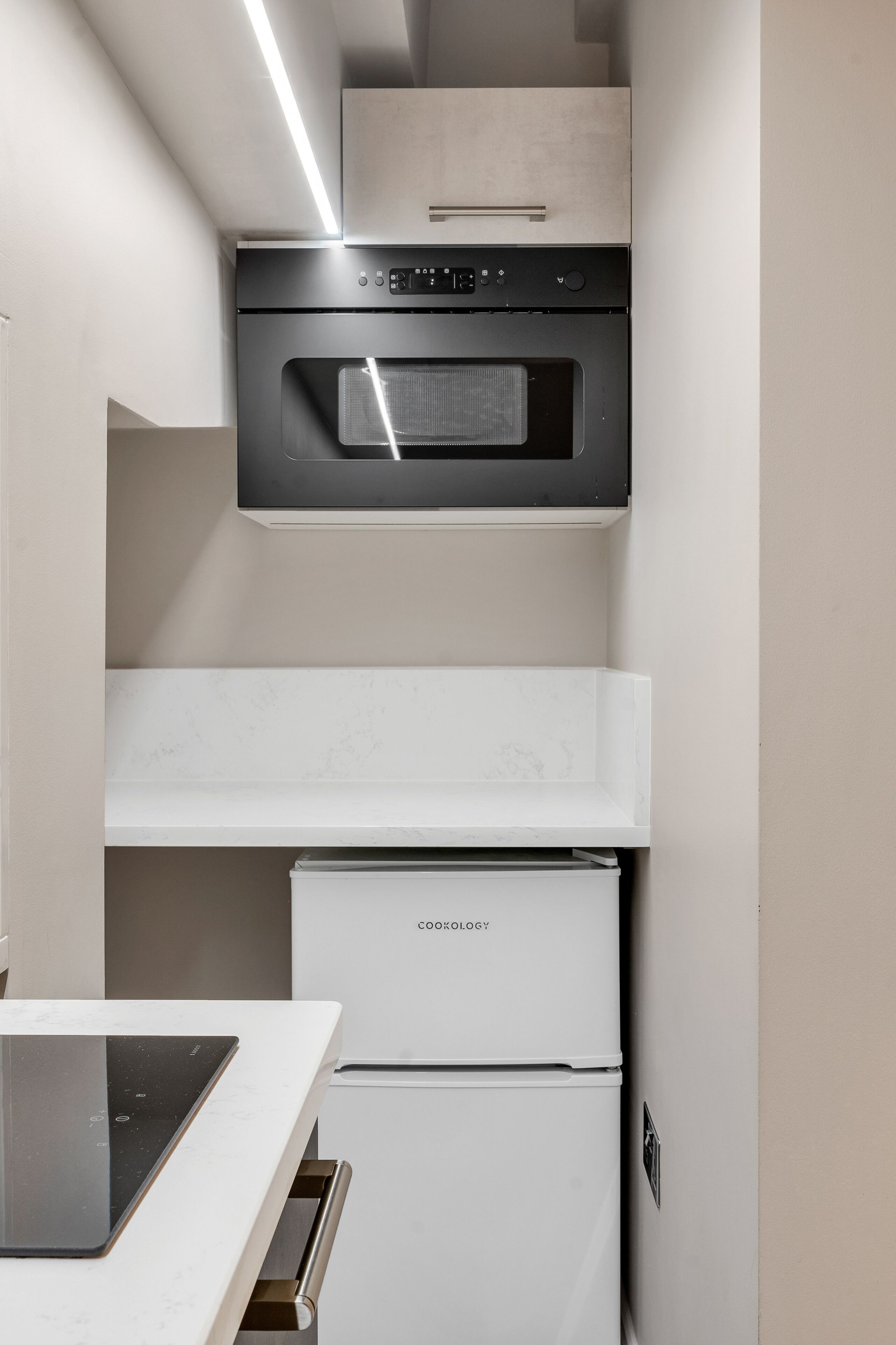 Uma cozinha compacta com forno embutido, micro-ondas e frigorífico.