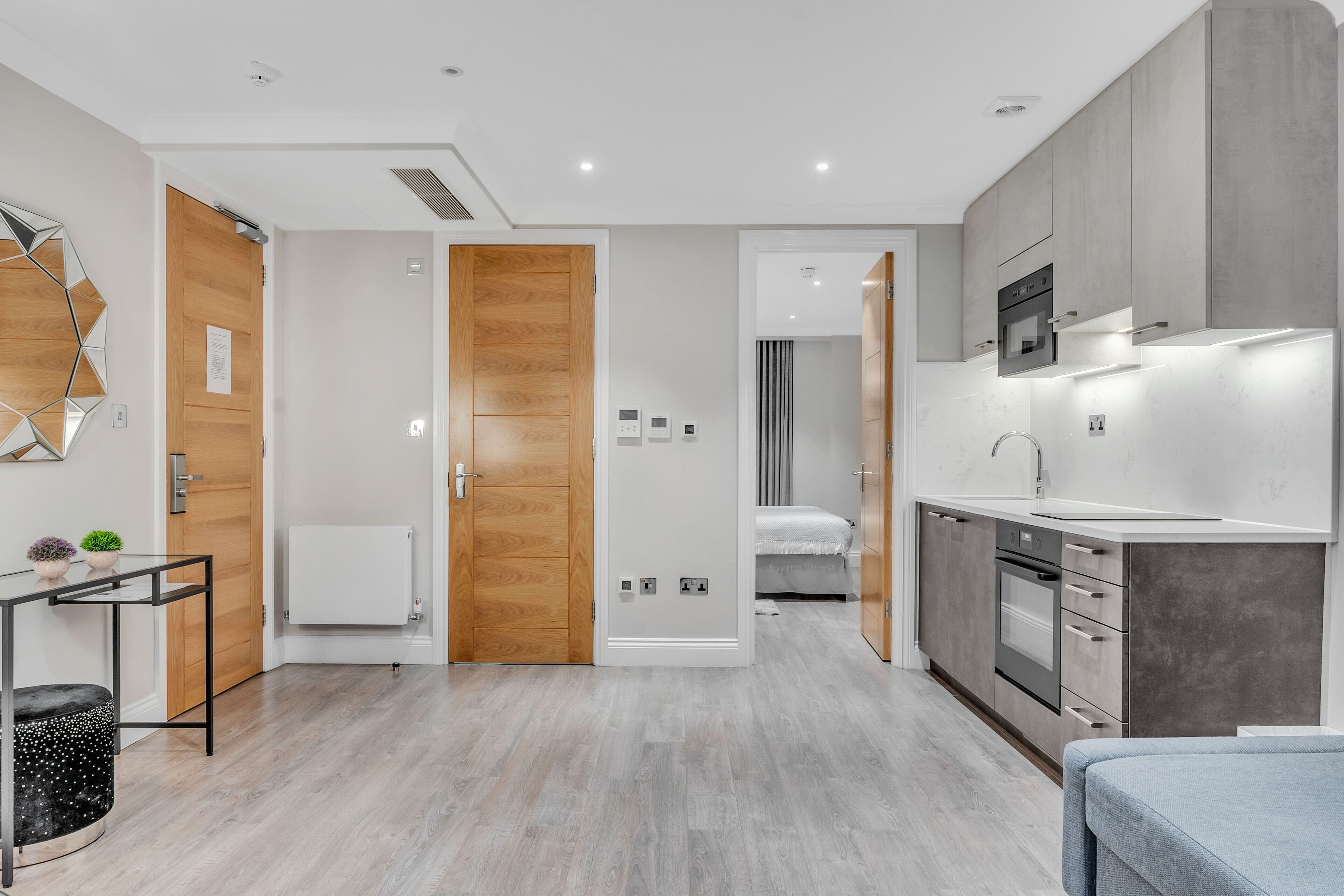 A modern kitchen with built-in appliances, a dining area with a table and chairs, and a bedroom with a bed and nightstand.
