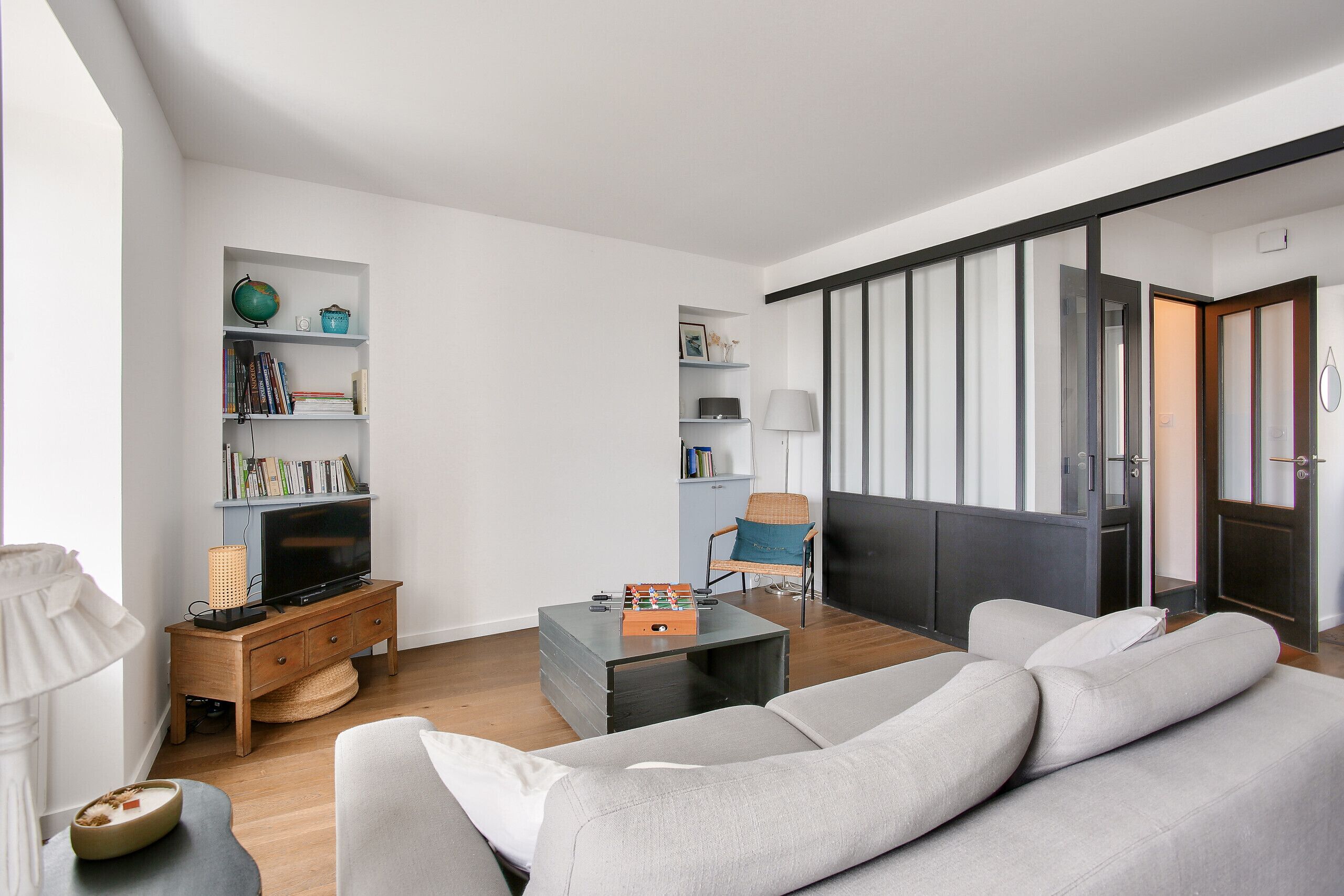 A modern living room with a sofa, coffee table, bookshelf, television, and a chair.