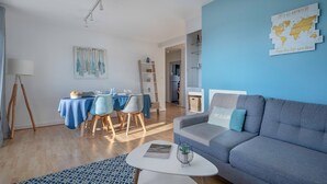 A modern living room with a grey sofa, a dining area with a blue tablecloth, and a world map on the wall. - Apartment for 4 in the heart of La Baule (La Baule-Escoublac)