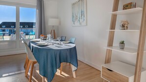 A dining area with a table set for four, a lamp, and a view of a pool and buildings outside. - Apartment for 4 in the heart of La Baule (La Baule-Escoublac)