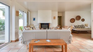 Uma sala de estar espaçosa com sofá, mesa de centro de madeira e lareira.