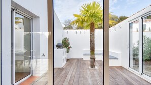 Um pátio moderno com deck de madeira, uma palmeira e uma parede branca com uma pequena prateleira.