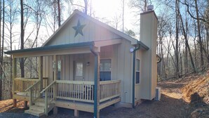 Une cabane avec une véranda, une étoile sur le toit et une cheminée.