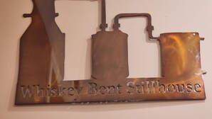 Une plaque métallique portant l’inscription « Whiskey Bent Stillhouse » et représentant la silhouette d’une distillerie.