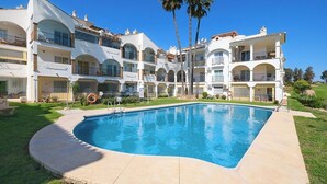 A multi-story hotel with a swimming pool, balconies, and palm trees. - Apartment in Siesta Golf (Mijas)