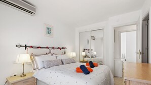 A bedroom with a bed, bedside tables, a mirror, and a wardrobe. - Apartment in Siesta Golf (Mijas)