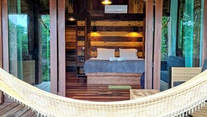 A wooden cabin with a hammock, a bed, and a view of the forest. - Tranquillité Dans Condominium Front de mer Barra Grande (Maraú)