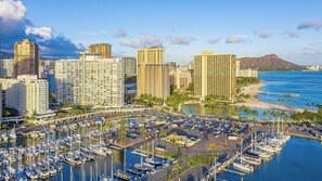 A marina with numerous boats docked, surrounded by high-rise buildings and a beach.