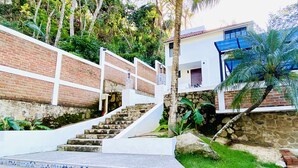 A staircase with patterned steps leading to a building with a stone wall and a palm tree.