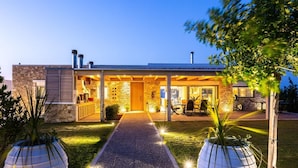 Ett modernt hus med en fasad av sten, en träveranda och en väl upplyst entré.