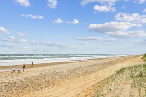 A beach with people walking, a sandy shore, and the ocean. - Heaven's Nest -- First Floor Duck Condo with direct access to Beach and Pool (Kitty Hawk)