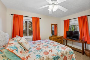 A bedroom with a bed, a television on a wooden stand, and a ceiling fan. - Heaven's Nest -- First Floor Duck Condo with direct access to Beach and Pool (Kitty Hawk)
