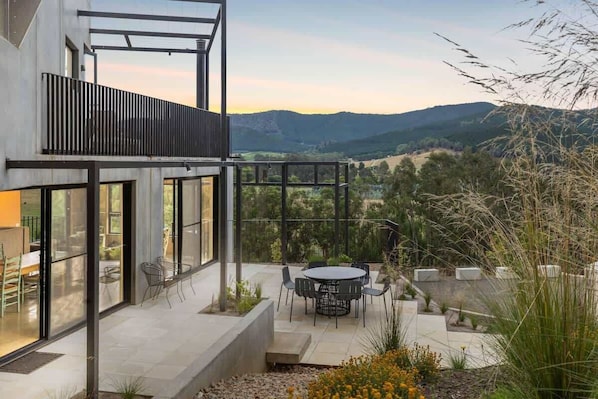Enjoy dining or socializing in this outdoor space with expansive views of the surrounding hills and trees.