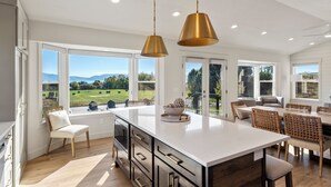 A spacious kitchen with a large island, pendant lighting, and a view of the countryside. - Gateway to Bear Lake (Sleeps 19) (Garden City)