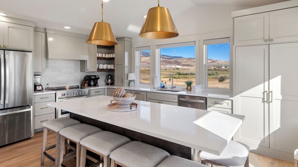A modern kitchen with a large island, stainless steel appliances, and a view of the countryside. - Gateway to Bear Lake (Sleeps 19) (Garden City)
