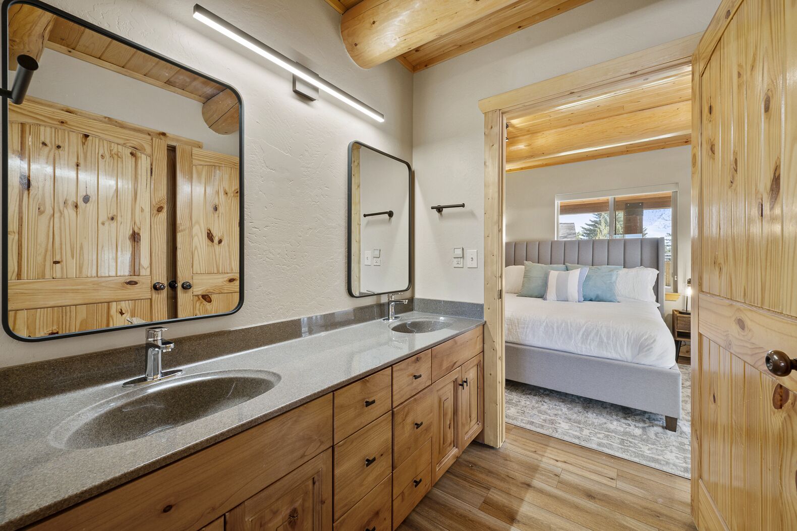 Un baño con armarios de madera, lavamanos doble y un espejo grande.