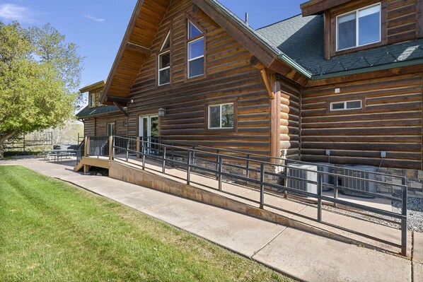 A log cabin with a porch, a covered patio, and a fenced walkway.