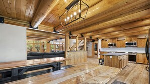 A spacious kitchen with wooden cabinets and a large island, a cozy seating area with a sofa, and a wooden dining table.