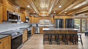 A spacious kitchen with wooden cabinets, stainless steel appliances, and a large island with bar stools.