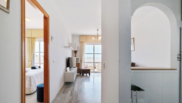 Quarto de hotel com cama, escrivaninha, cadeira, mesinha e janela.