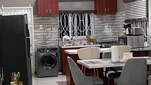 A modern kitchen with a built-in washing machine, a dining area with a marble table, and pendant lights. - Sky View Villas @ Edmund Ridge Estate (Montego Bay)