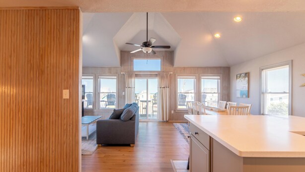 A spacious kitchen with a central island, wooden flooring, and a ceiling fan.