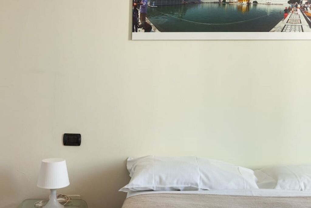 Een hotelkamer met een bed, een nachtkastje met een lamp en een lijst met een uitzicht op het water.