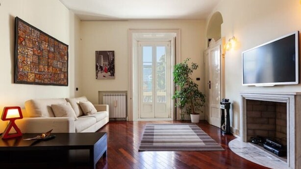 A living room with a sofa, a coffee table, a TV, a fireplace, and a door leading to another room.