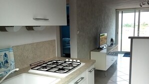 A modern kitchen with white cabinets, a gas stove, and a large window. - Galv Ar Mor, Petite Maison Cosy Proche Plage (Cléder)