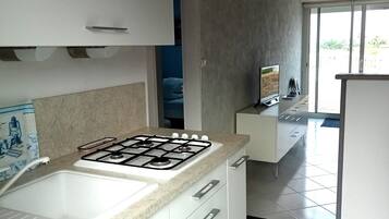 A modern kitchen with white cabinets, a gas stove, and a large window.