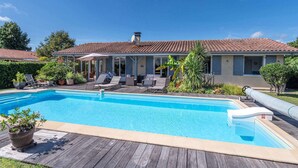 A poolside area with a pool, lounge chairs, and a covered patio.